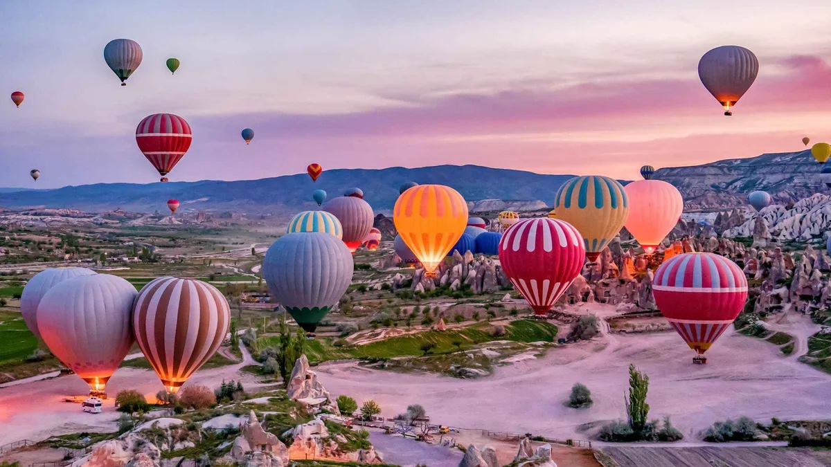 Hot air balloons rising over Goreme at sunrise on a 3-day Cappadocia Turkey tour package from Istanbul, Goreme, Turkey