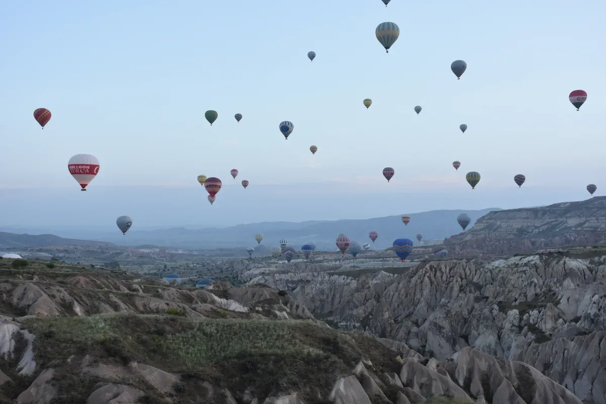 Hot air balloons over the valleys near Goreme at dawn, in a guide to the best time to visit Turkey
